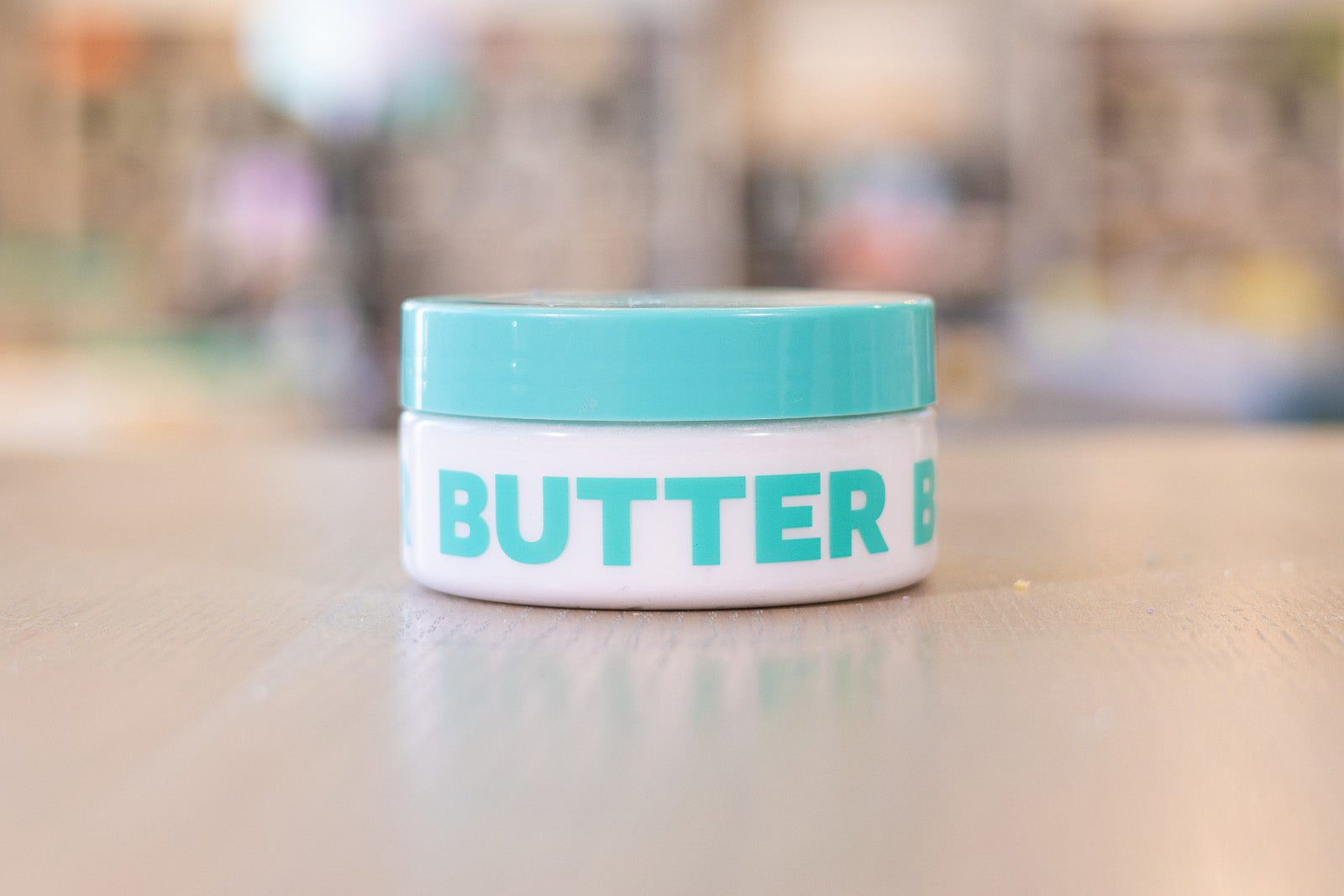 Container with teal lid filled with Body Butter