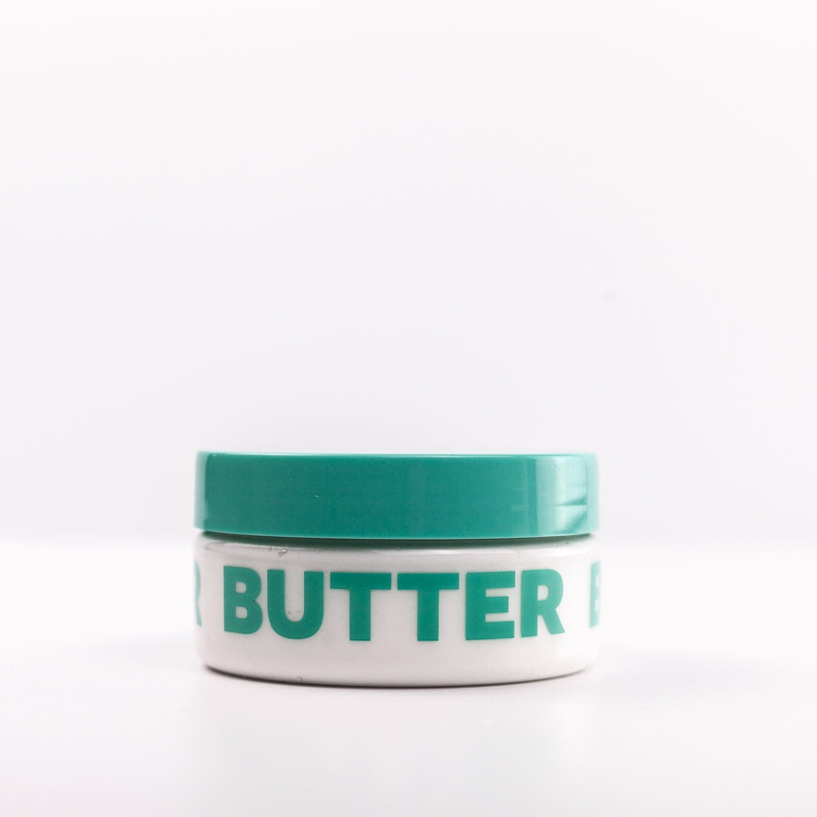 Clear Body Butter container with teal lid and lettering on white background 