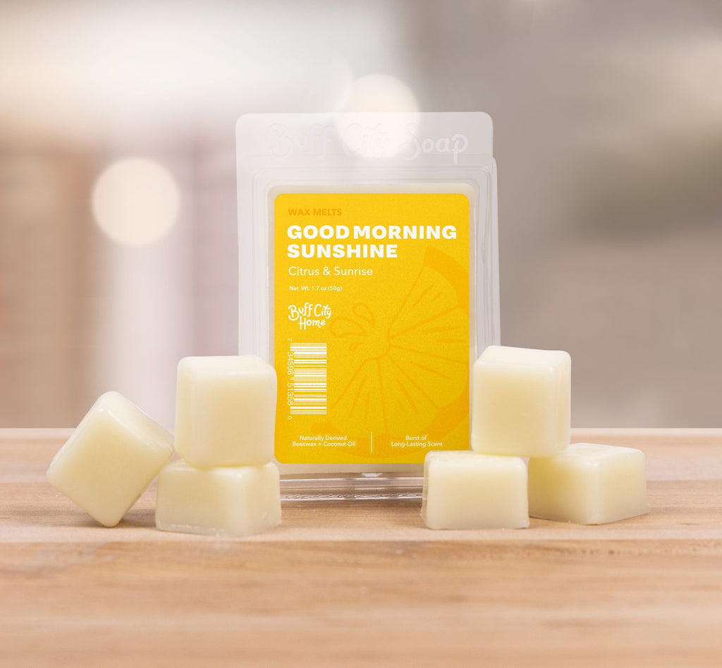 Light yellow Wax Melts stacked into triangles next to clear, yellow packaging on counter