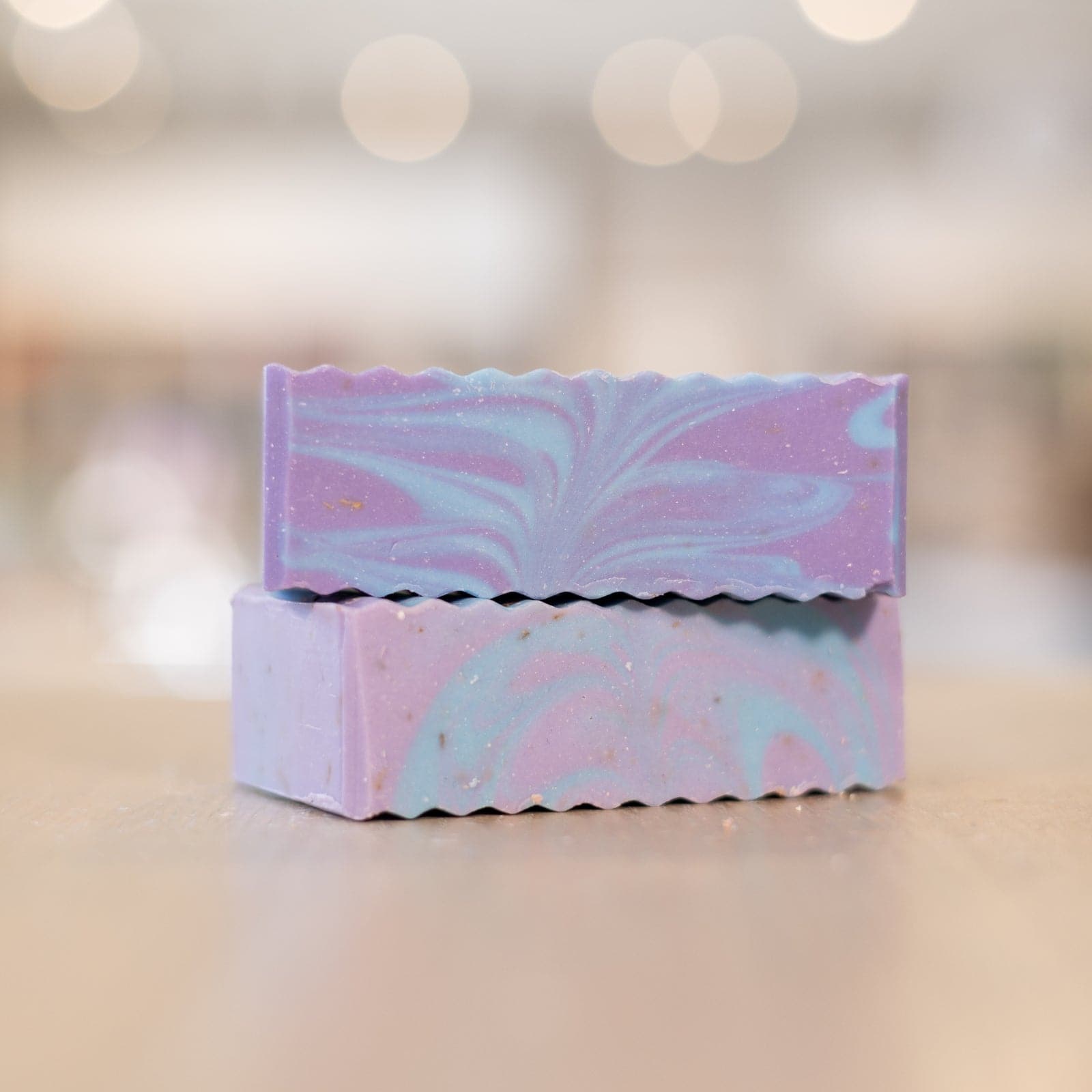 Two bars of Buff City Soap's lavender colored with blue and purple swirls stacked a top each other