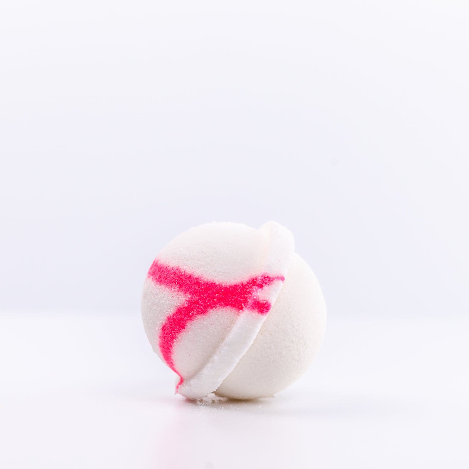 one white Mermaid Bath Bomb placed on its side with a pink "X" design on it