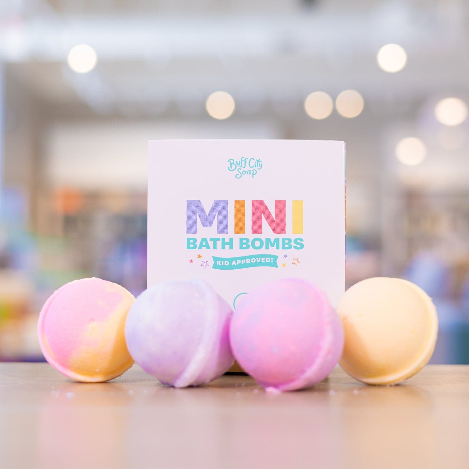 box that says Mini Bath Bombs with 4 pink and orange Mini Bath Bombs placed in front of it