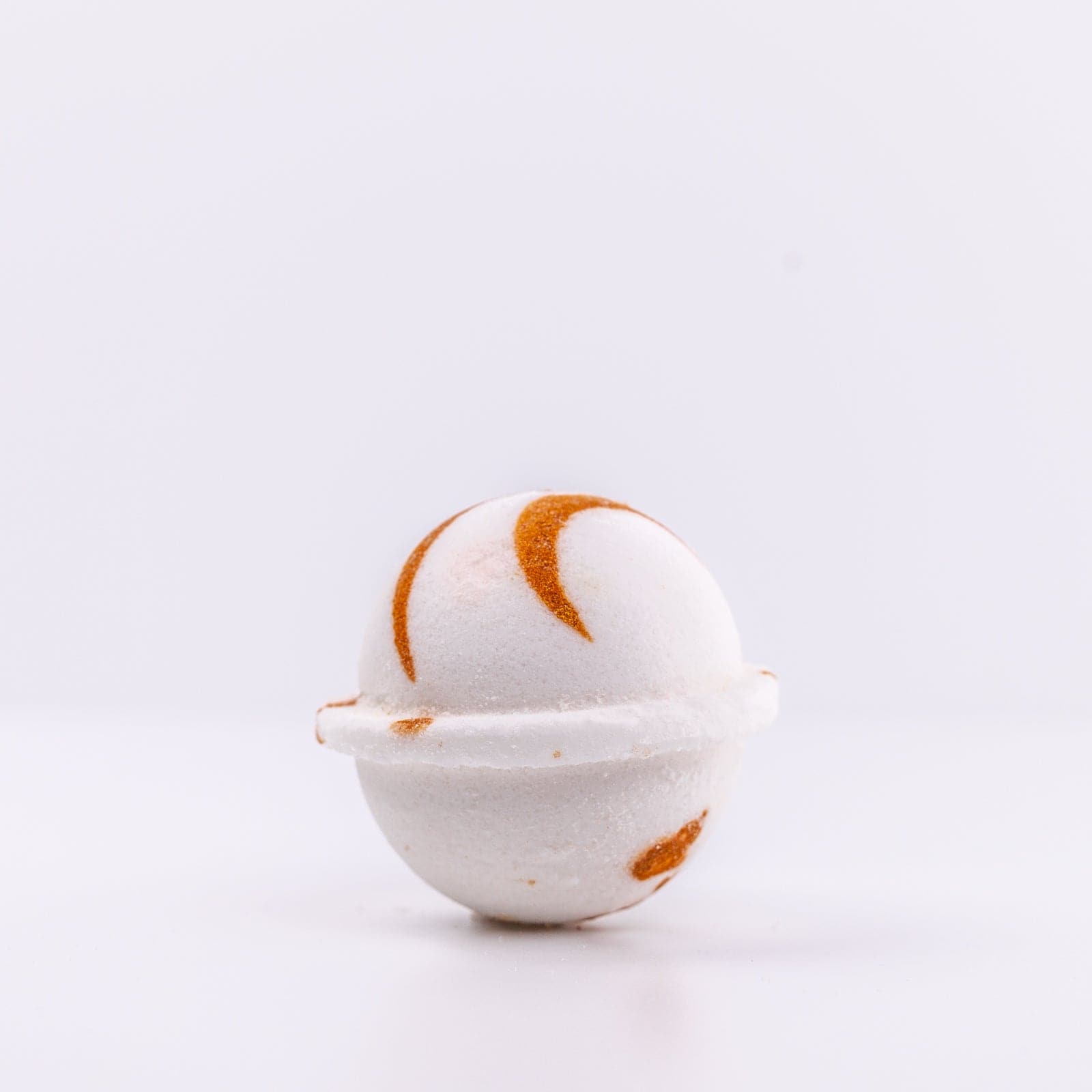 a white Narcissist Bath Bomb, with caramel design, placed upright