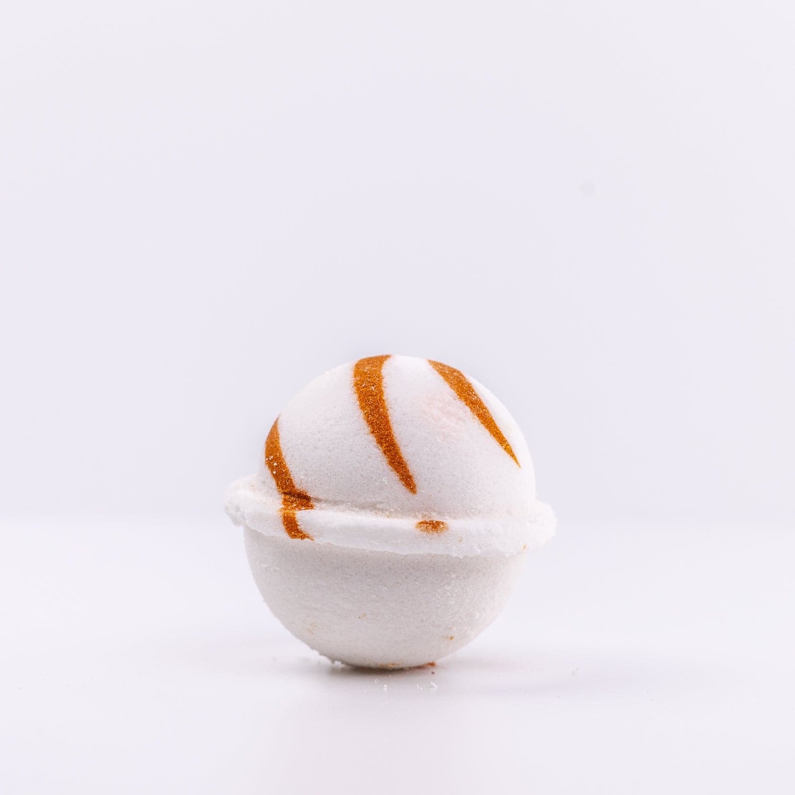 a white Narcissist Bath Bomb, with caramel design, placed upright