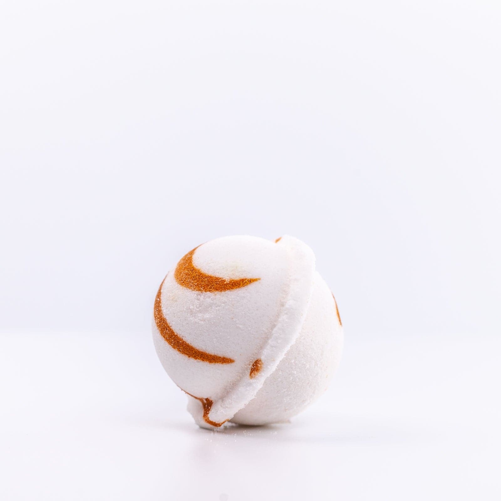 a white Narcissist Bath Bomb, with dark orange design, placed on it's side