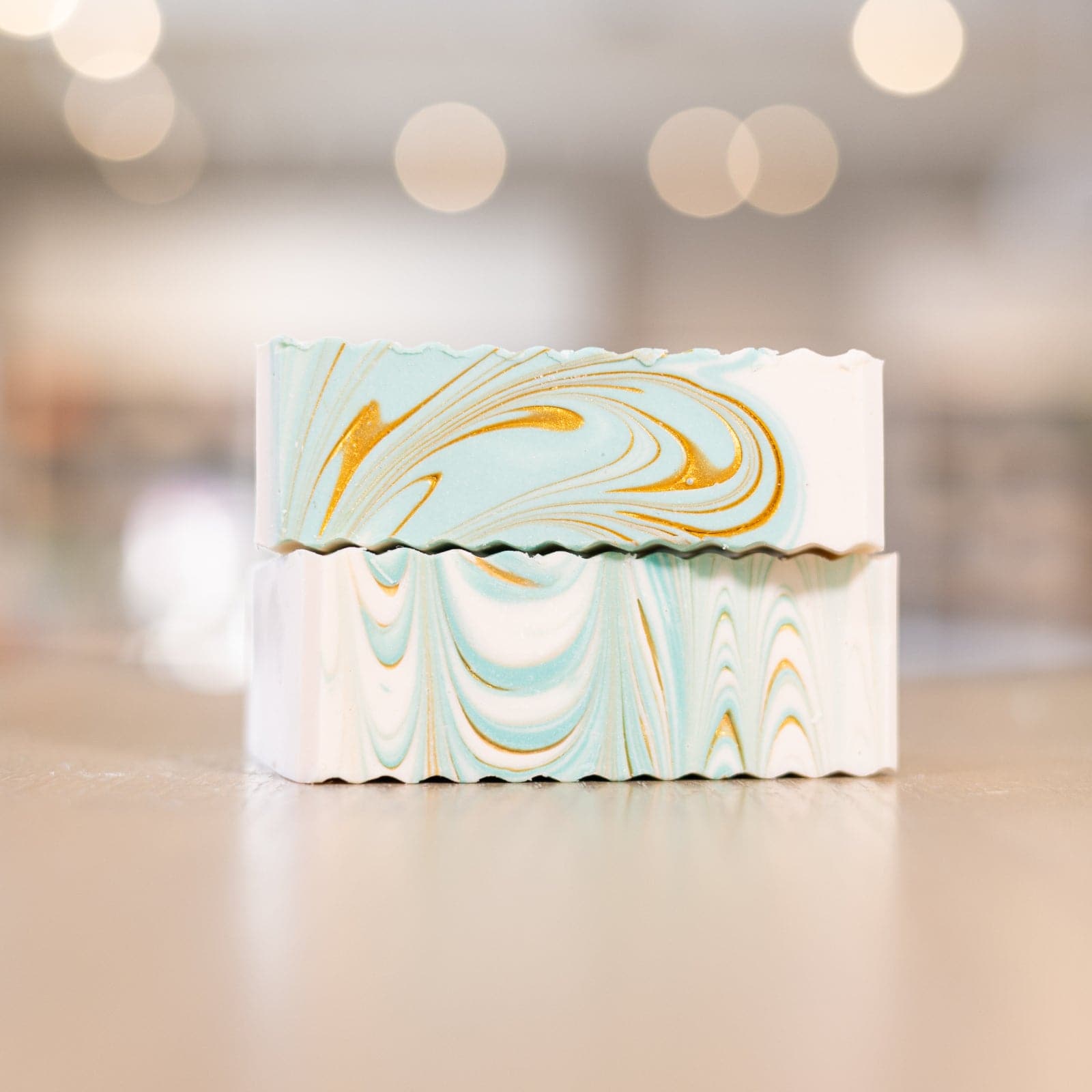 two teal, white, and orange Narcissist Shea Butter Soap Bars stacked on top of each other